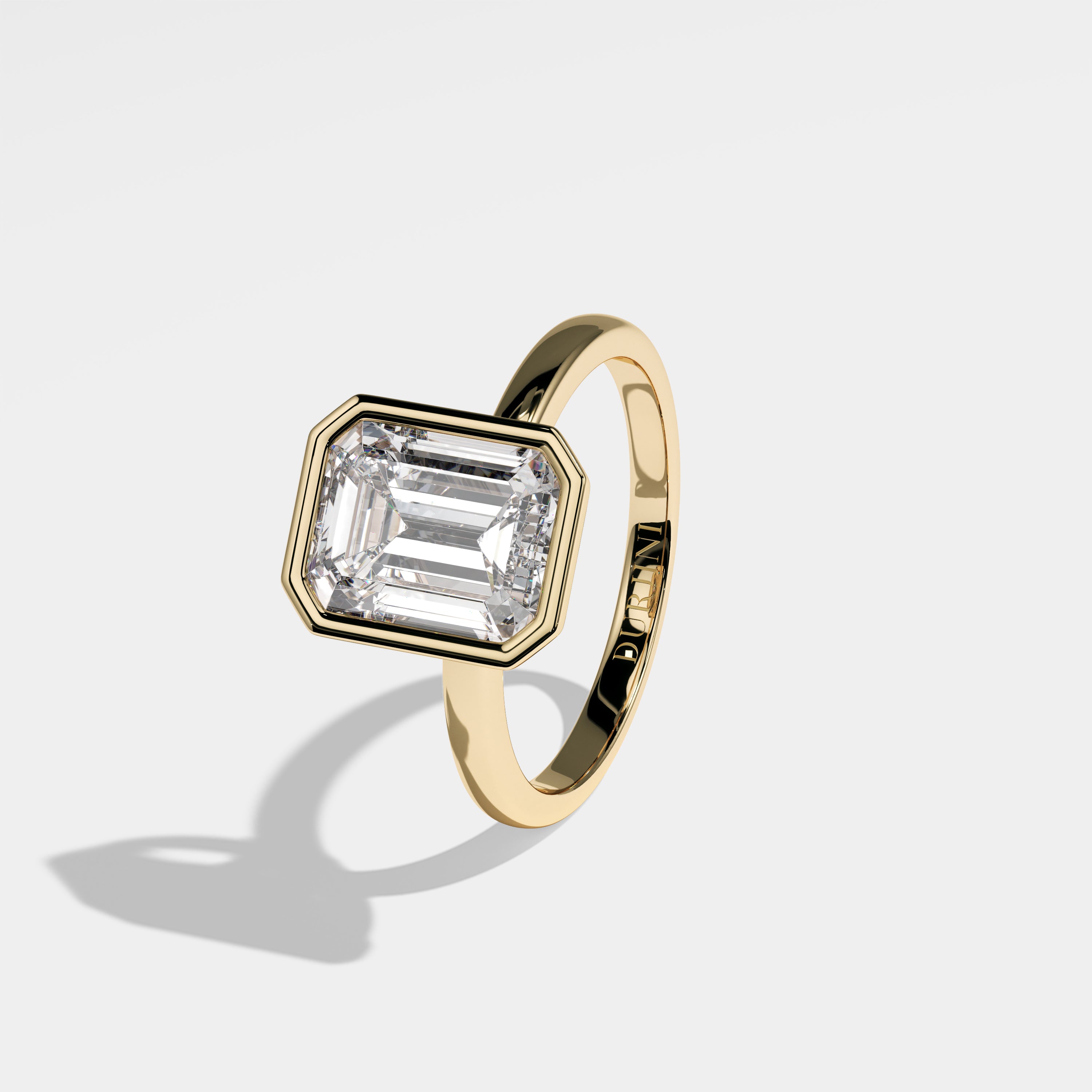 High emerald-cut diamond engagement ring in 18K yellow gold by Kurbãni Durjini, left view